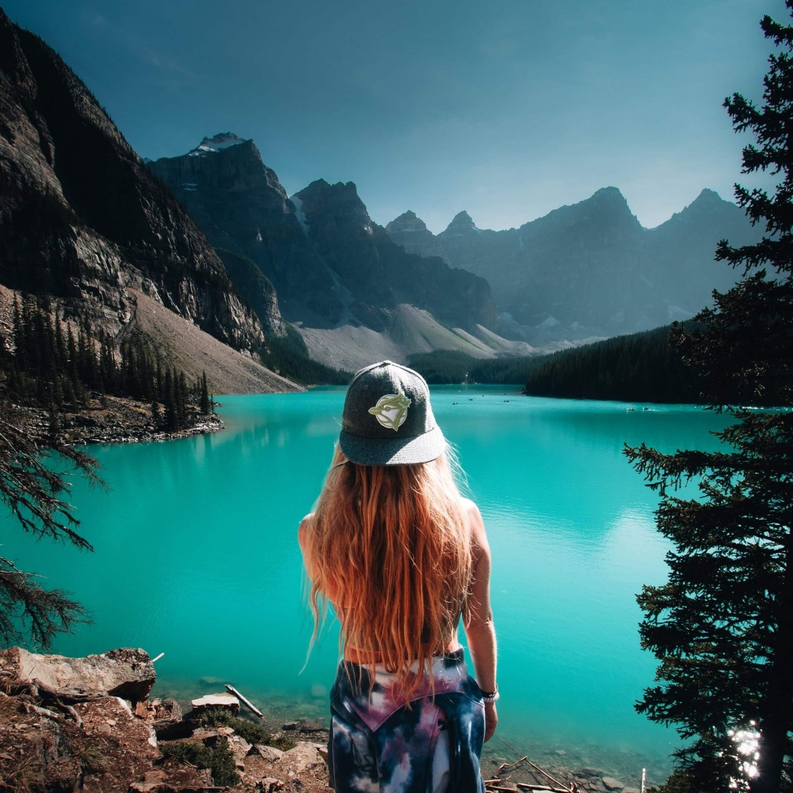 A traveler looking across a turquoise mountain lake